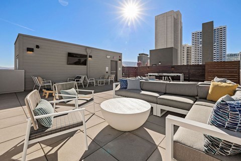 a rooftop patio with furniture and a city in the background