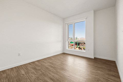 an empty living room with a window and wood floors