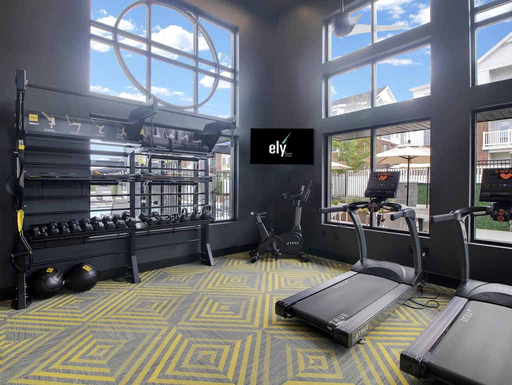 a workout room with cardio equipment and large windows