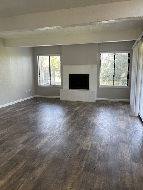 an empty living room with wood floors and a fireplace