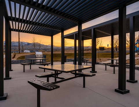 A patio with tables and benches is set up under a roof.