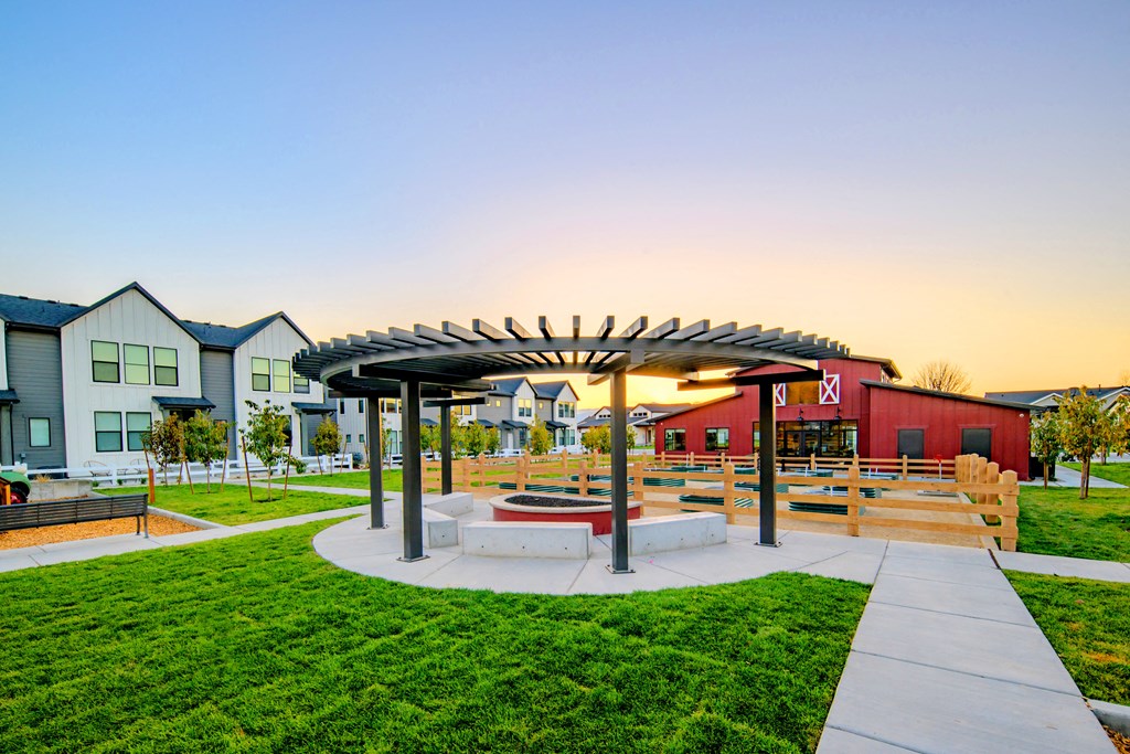 a picnic area with benches and a fire pit at sunset