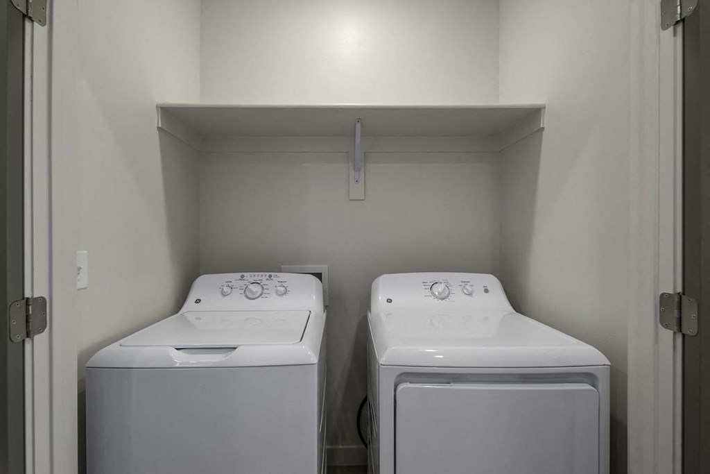 a white laundry room with two washes and a dryer