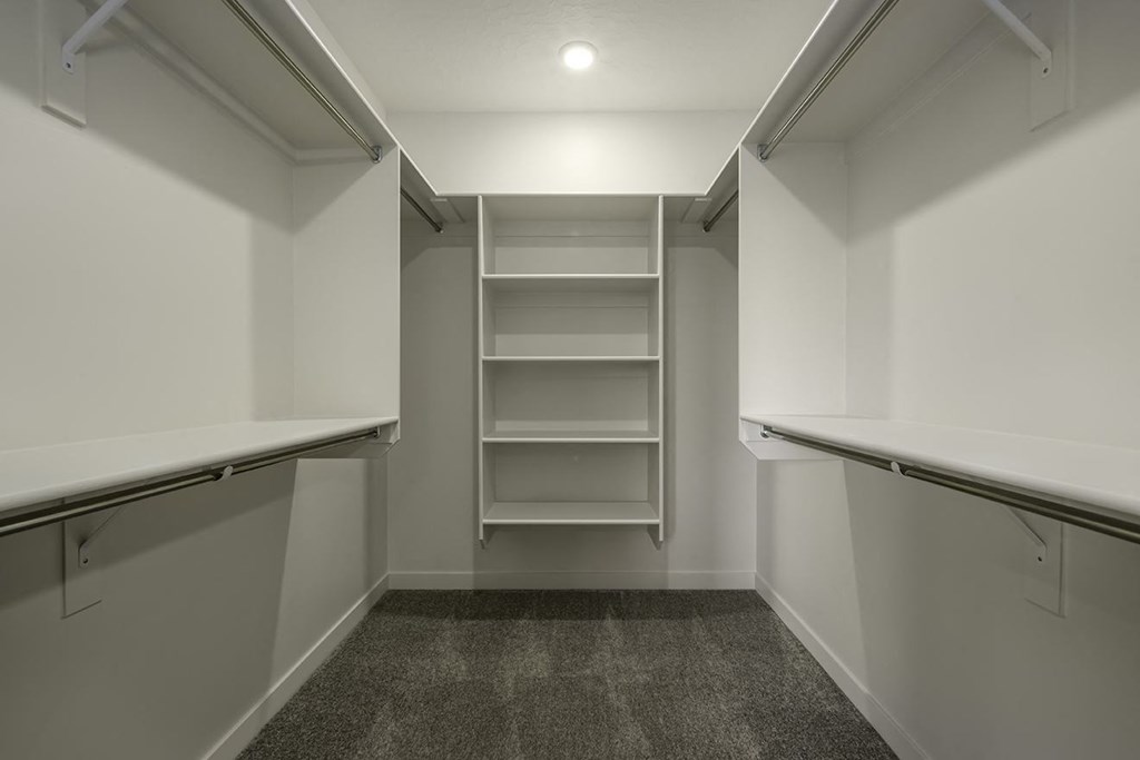 a walk in closet in a home with empty shelves