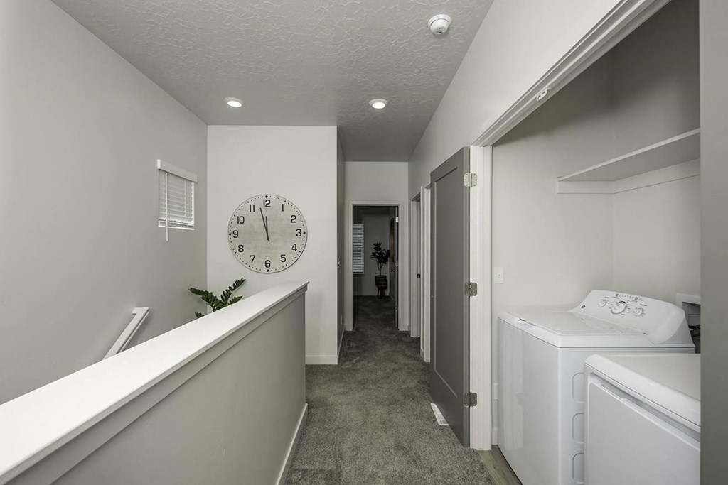 a white laundry room with a large clock on the wall
