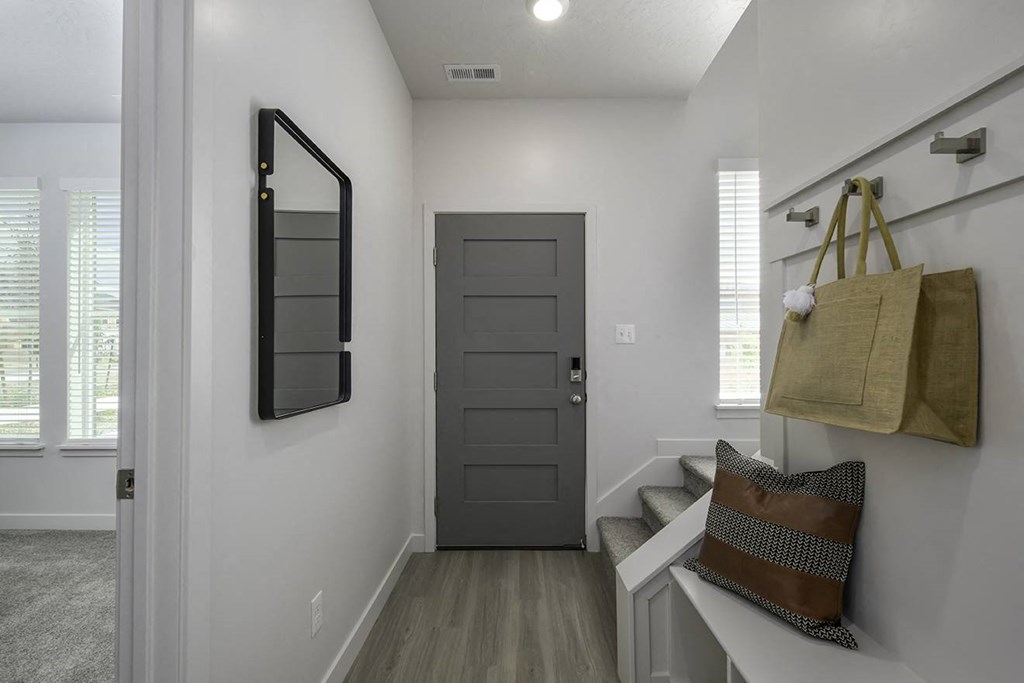 a white hallway with a black door and bags on the wall