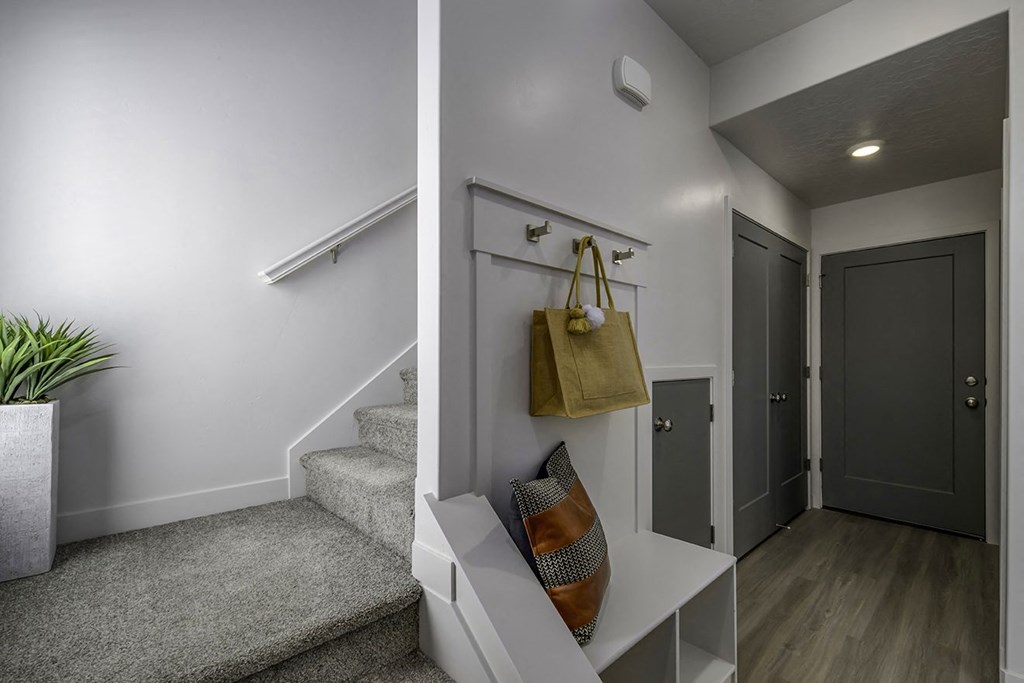 a hallway with stairs and a door and a bag hanging on the wall