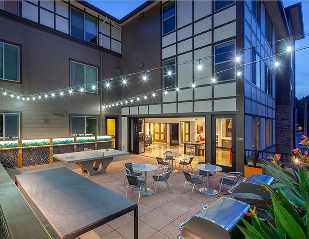 A patio with a pool table and chairs is lit up with string lights.