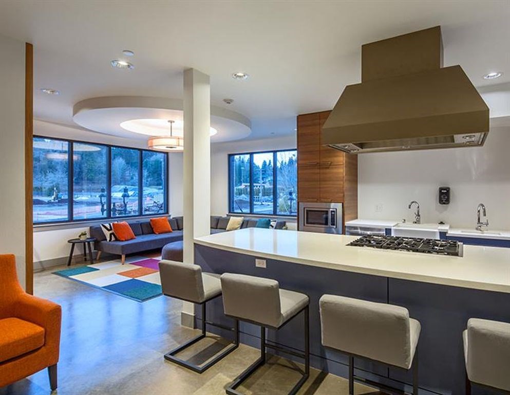 A modern kitchen with a bar area and a view of trees outside the windows.