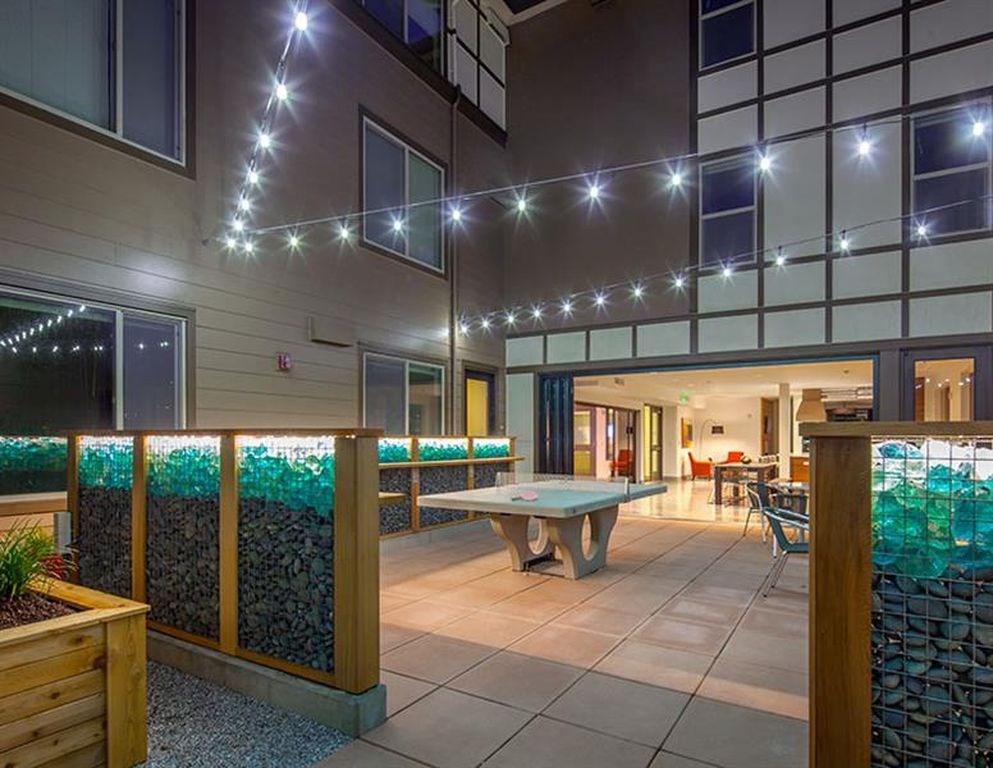 A patio area with a table and chairs under string lights.