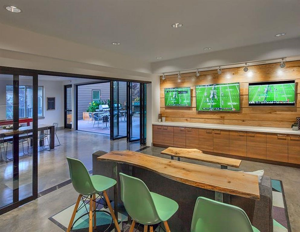 A room with a long table and chairs with a television on the wall.