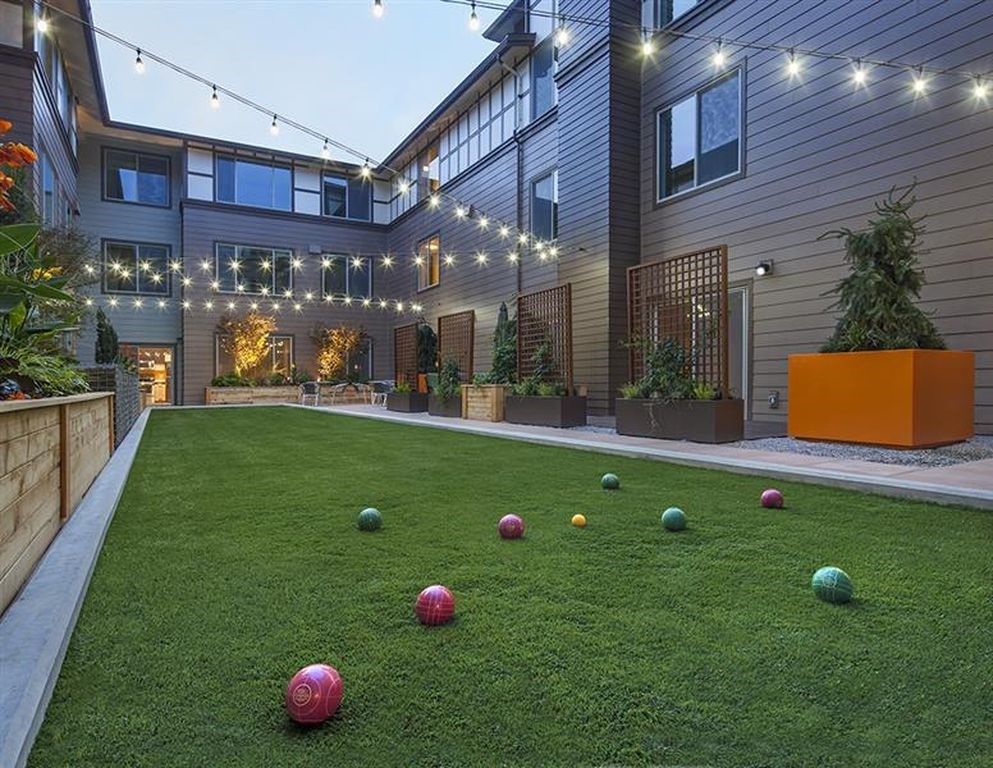 A backyard with a lawn and a building in the background.