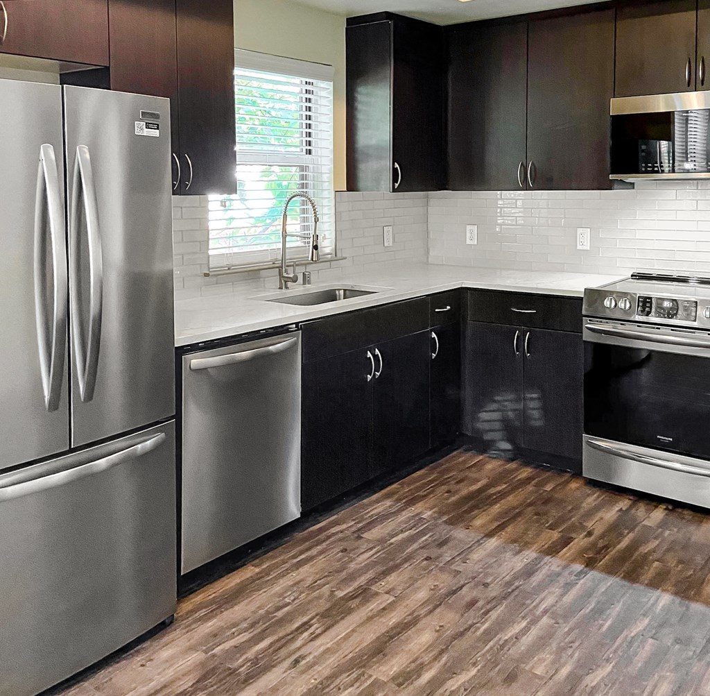 a kitchen with stainless steel appliances and wooden floors