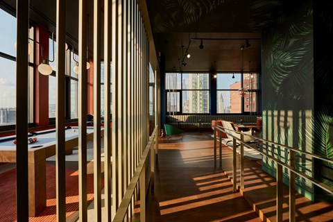 A long hallway with a pool table and a green plant on the wall.