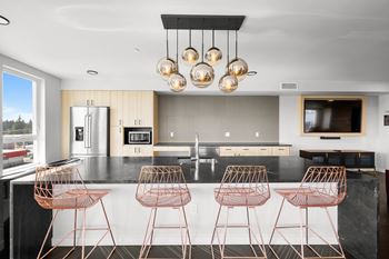 a modern kitchen with copper bar stools and a large island at Ion Town Center, Shoreline, WA