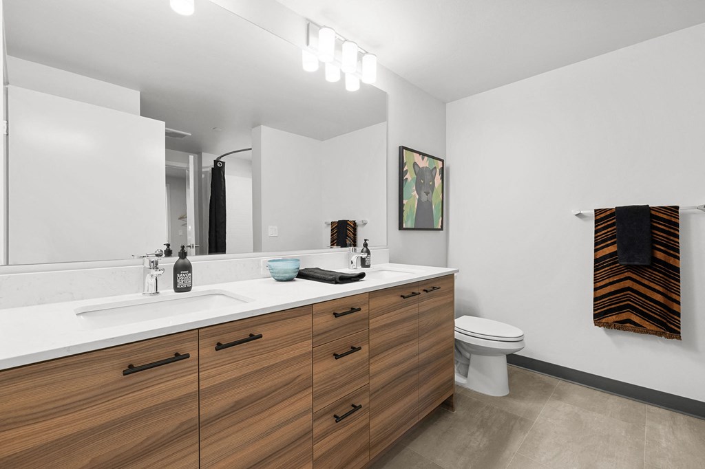 a bathroom with white walls and a wooden vanity with two sinks and a toilet at Ion Town Center, Shoreline, WA 98133