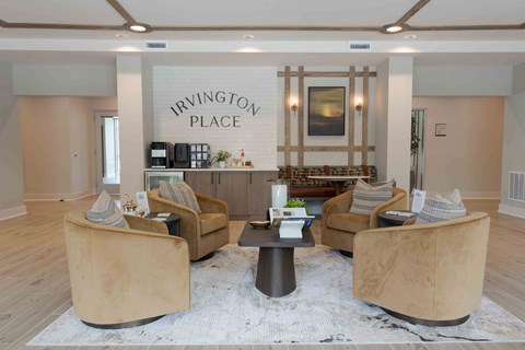 A living room with a coffee table and chairs in front of a sign that says Irvington Place.