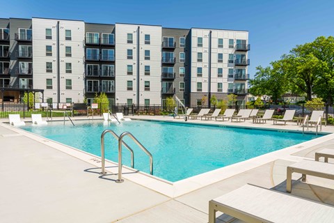 A swimming pool in front of a modern apartment building.