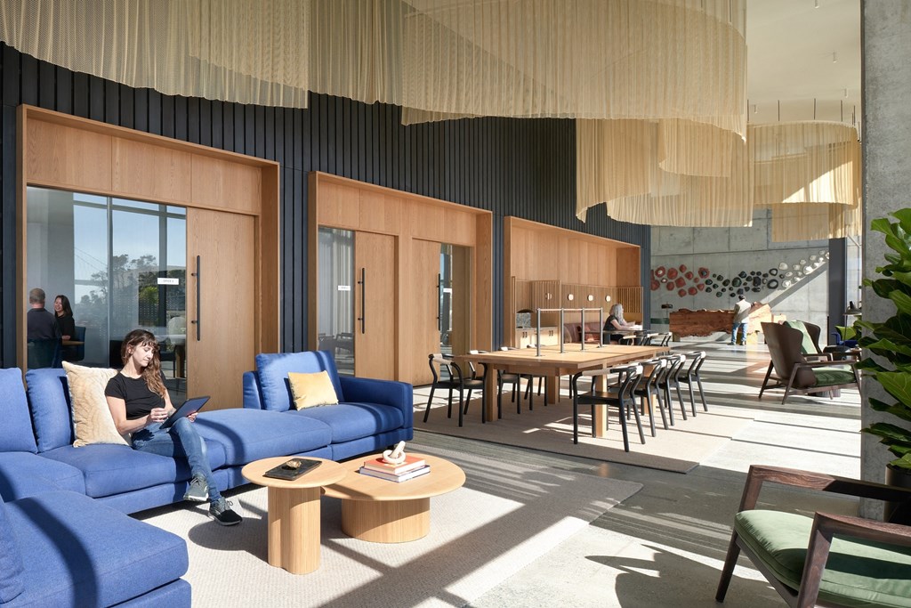 a woman sitting on a couch in a lobby with a laptop