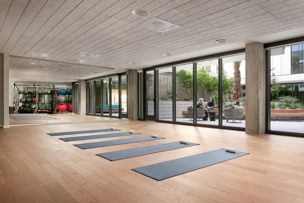 a yoga room with blue yoga mats on the floor and glass doors