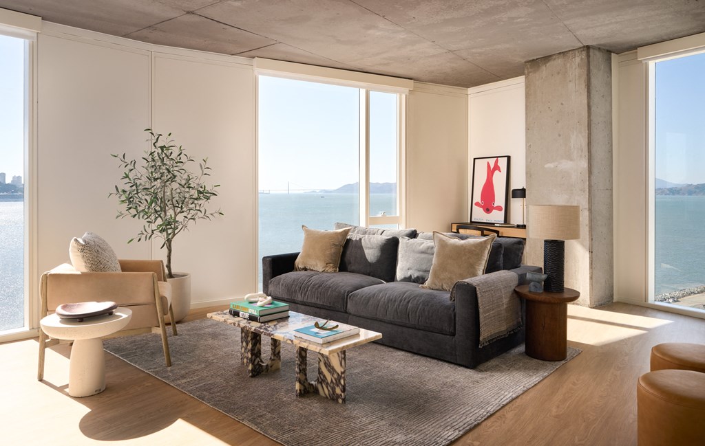 a living room with a gray couch and a view of the ocean