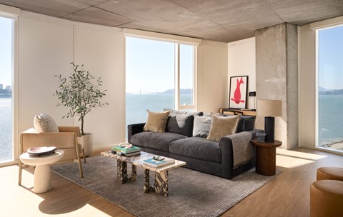 a living room with a gray couch and a view of the ocean