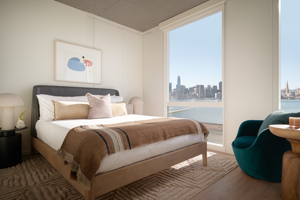 a bedroom with a view of the water and a bed and a chair