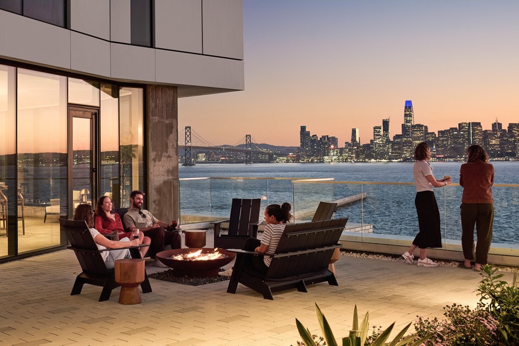 a group of people sitting around a patio with a view of a city and water