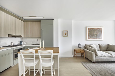 A modern kitchen with white chairs and a dining table.