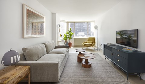 A living room with a grey couch, a yellow chair, a wooden coffee table, and a grey cabinet.
