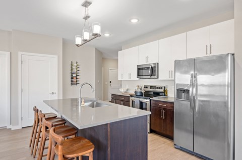A kitchen with a stainless steel refrigerator and wooden chairs.