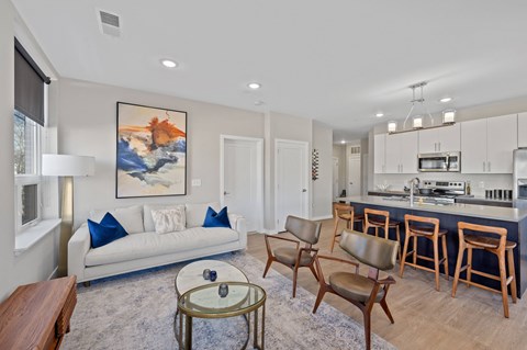 A living room with a white couch and a painting on the wall.