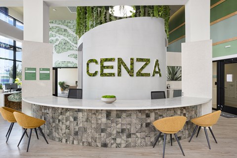 the lobby of a cement building with a reception desk and chairs