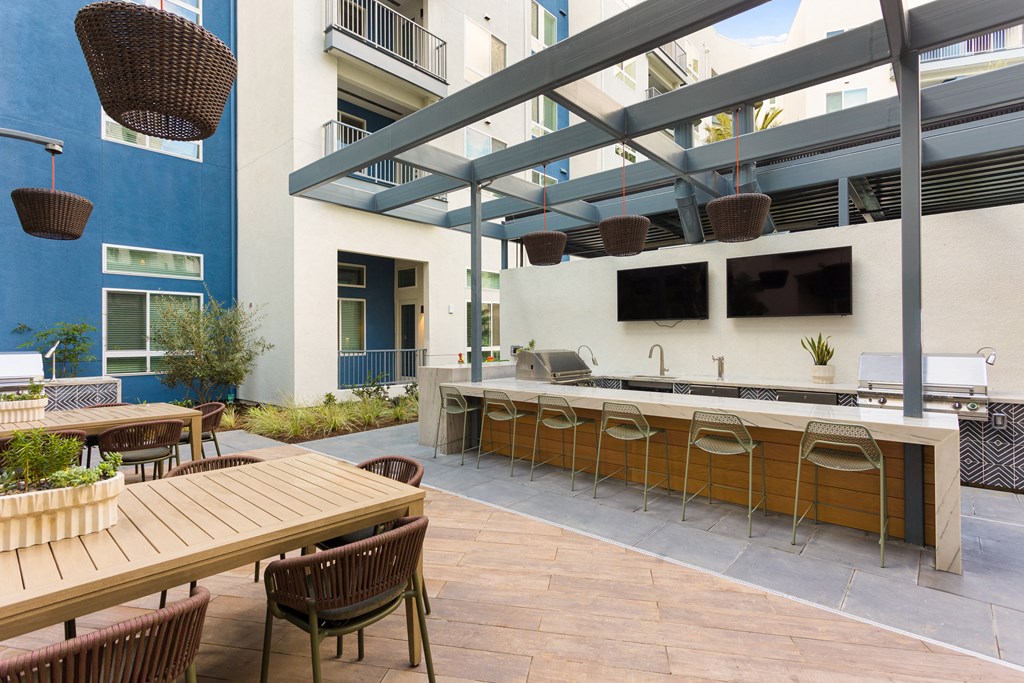a communal patio with tables and chairs and a bar with a television