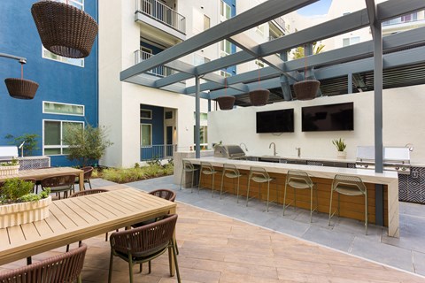 a communal patio with tables and chairs and a bar with a television
