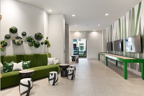 a lobby with green couches and tables and a television