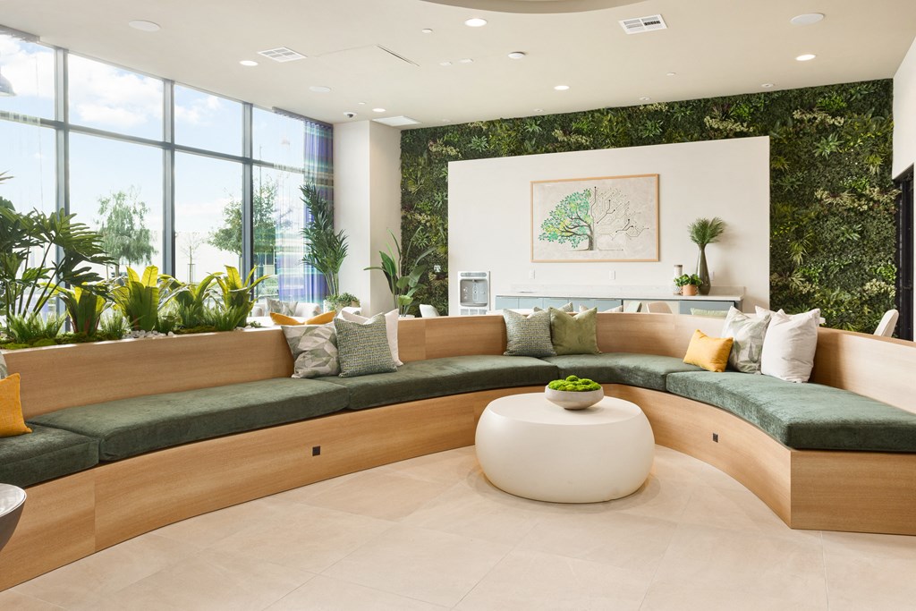 a living room with large windows and a wall of plants