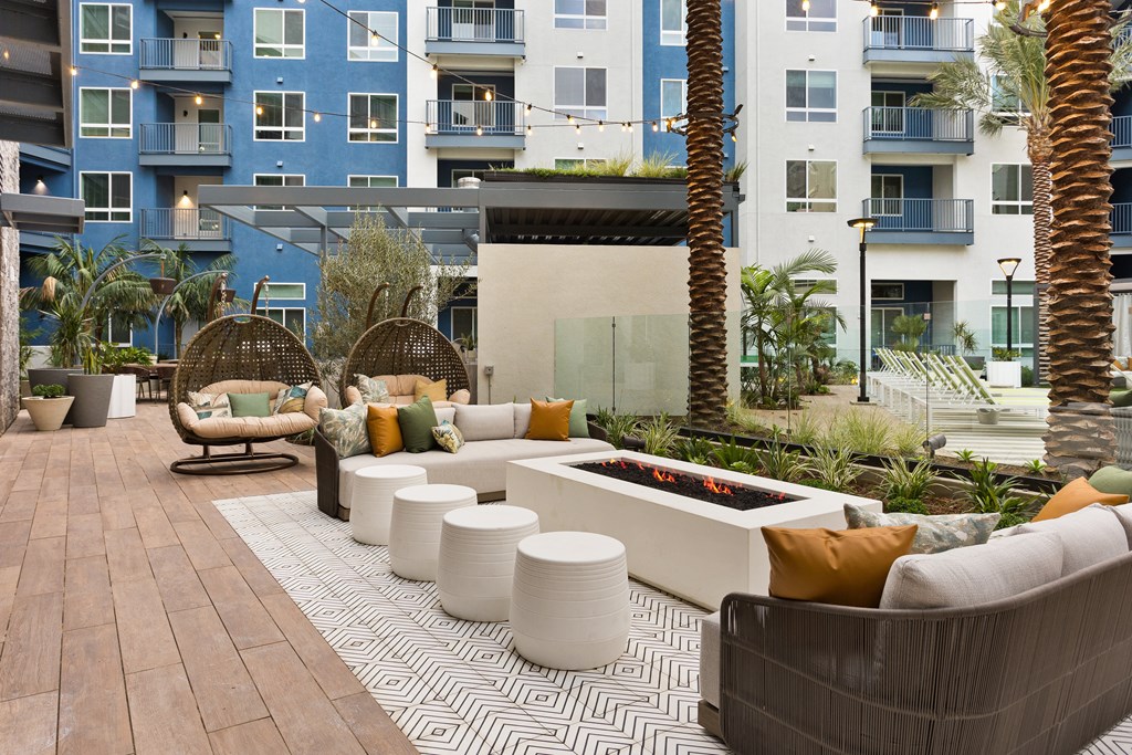 a seating area with couches and tables in front of an apartment building