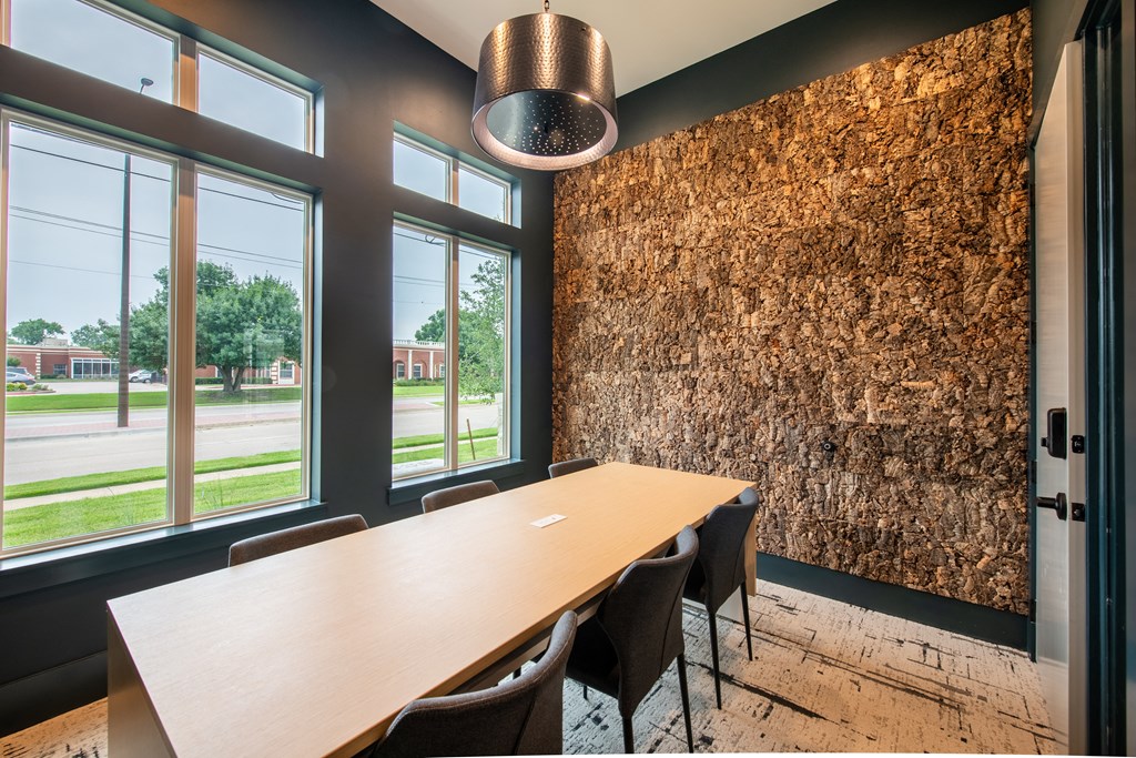 a conference room with a long wooden table and chairs and a wall of logs