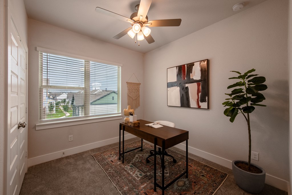 an office with a large window and a ceiling fan