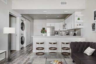 a kitchen with white cabinetry and a white counter top next to a living room with a at Copper 87, West Jordan, 84088