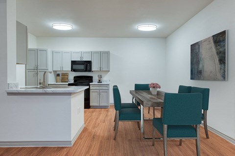 A kitchen with a table and chairs in front of a painting.