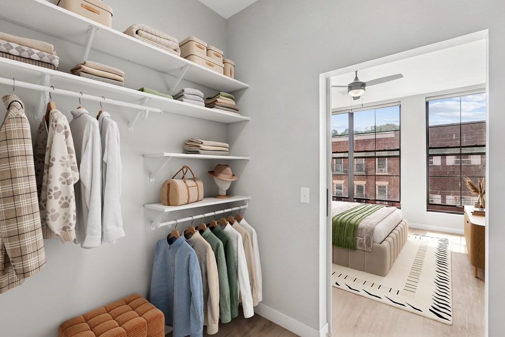 A white closet with clothes and a window.