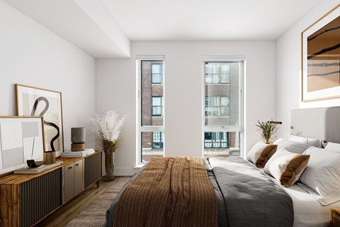 A bedroom with a large bed and a window overlooking a building.