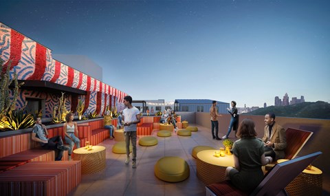 A group of people are sitting and standing on a rooftop terrace.