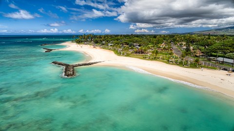 A beautiful beach with clear blue water and a sandy shore.