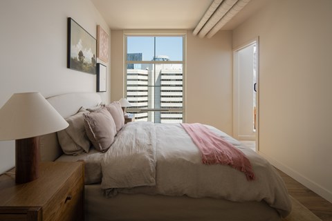 A bedroom with a large bed and a window with blinds.