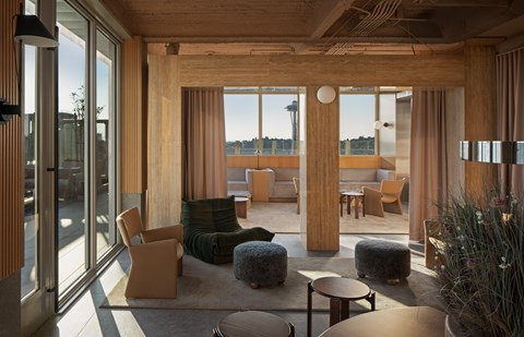 A modern living room with wooden furniture and large windows overlooking a body of water.