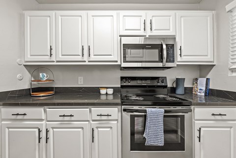 A kitchen with white cabinets and a black stove top.