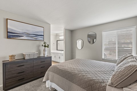 A bedroom with a large bed and a painting on the wall.